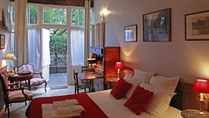 A hotel room with a bed, a desk, chairs, and a view of the outdoors. - Les Chambres de Mathilde (Angers)