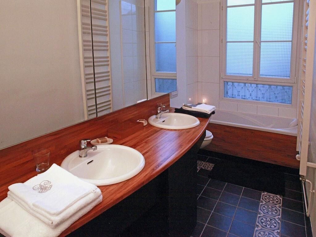 Un baño con dos lavamanos, un espejo grande y una bañera.