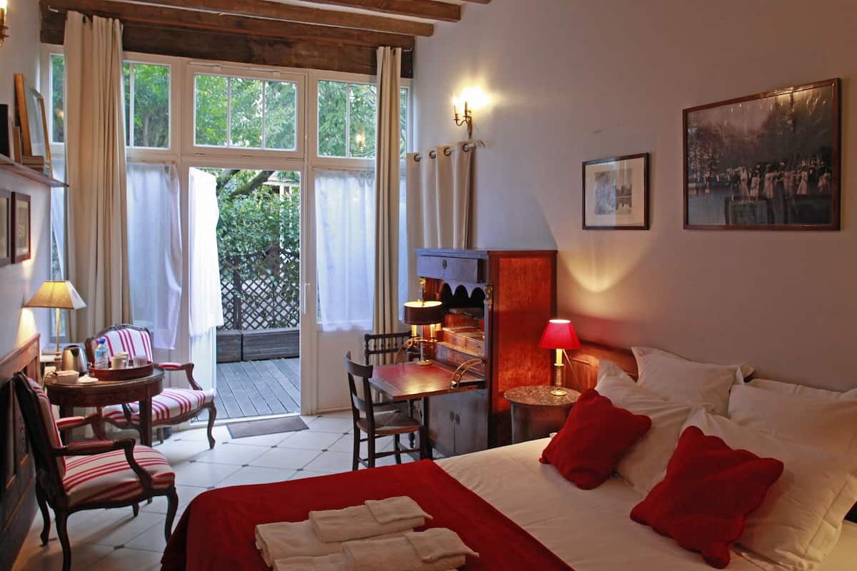 Una habitación de hotel con una cama, un escritorio, una silla, una mesa, una lámpara y un cuadro en la pared.