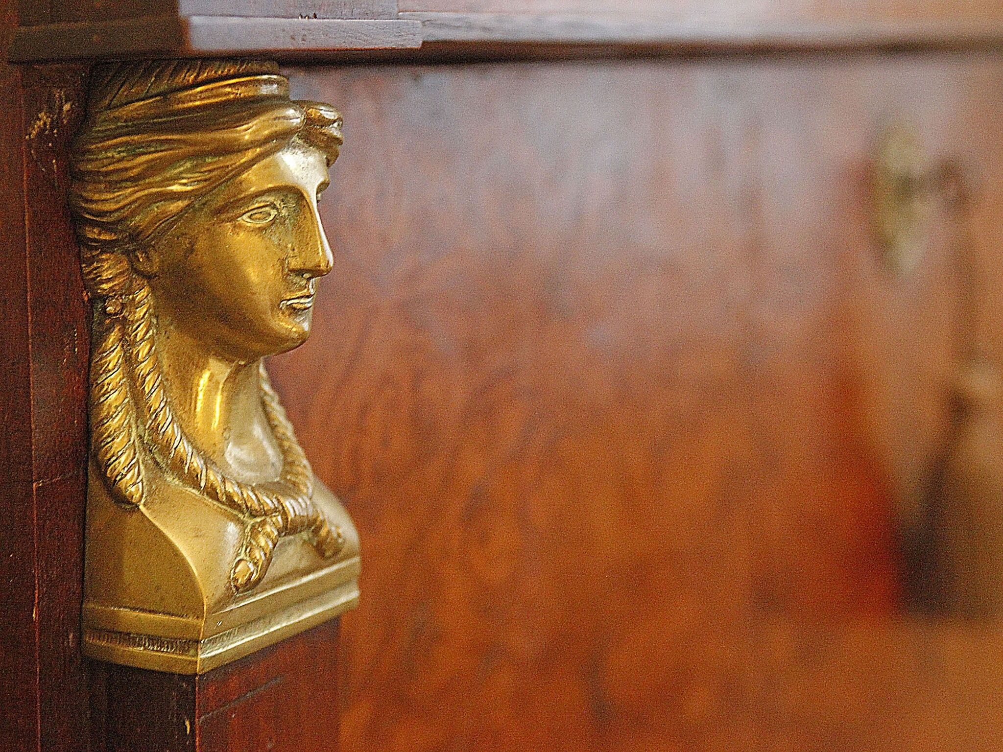 A golden bust sculpture mounted on a wooden surface.