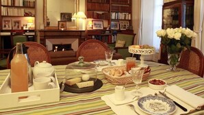A dining table set with breakfast items, surrounded by bookshelves and a fireplace. - Les Chambres de Mathilde (Angers)
