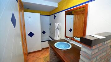 Un baño con un lavamanos azul, tocador de madera y un espejo.