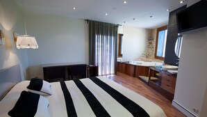 Una habitación de hotel moderna con una cama grande, un escritorio, un muro decorativo de piedra y un televisor.