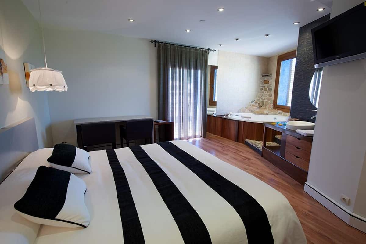Ein modernes Hotelzimmer mit einem großen Bett, einem Schreibtisch, einer Wand mit Steinverkleidung und einem Fernseher.