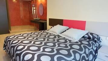Una habitación de hotel moderna con una cama grande, un baño pequeño y una pared de acento roja.