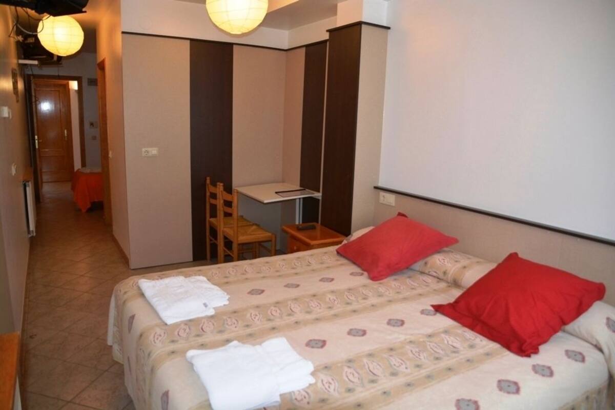 Ein Hotelzimmer mit zwei Betten, einem Schreibtisch und einem Stuhl.