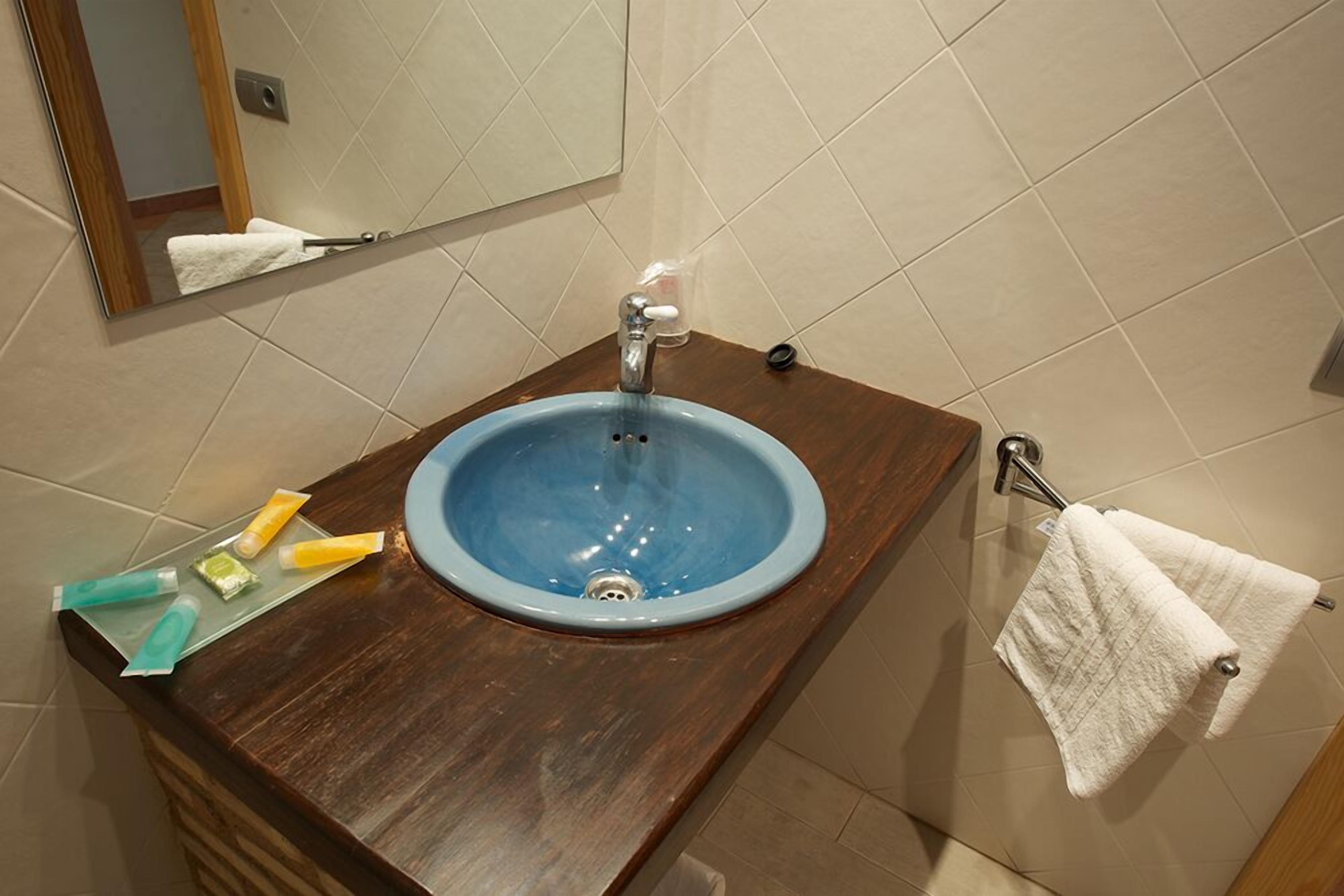 A bathroom with a blue sink, wooden countertop, and a towel hanging on a rack.
