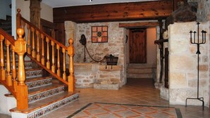 Un interior rústico con una escalera de madera, paredes de piedra y suelo de baldosas.