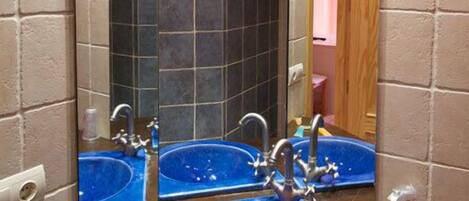 Un baño con dos lavamanos azules, un espejo y una puerta de madera.
