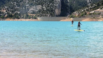 A coastal scene with a large dam and people paddleboarding.