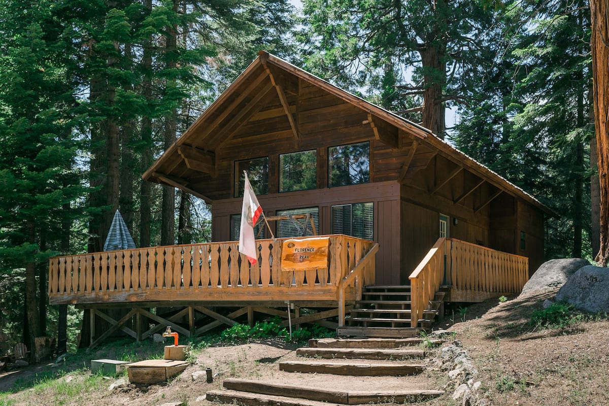 A wooden cabin with a balcony, a flag, and a sign that reads "Florence Peak."