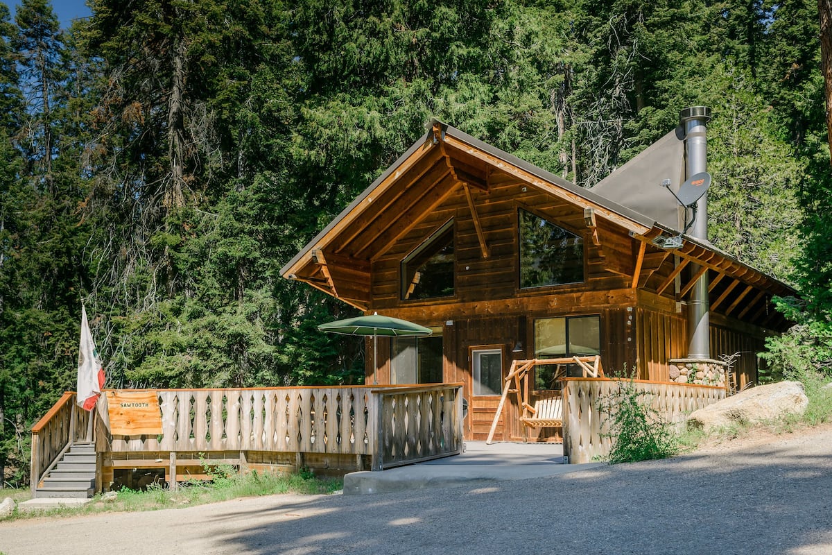 A wooden cabin with a balcony, a chimney, and a flag.