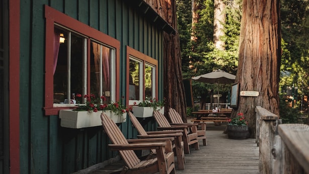 A wooden deck with Adirondack chairs, a wooden building with red trim, and a sign indicating a restroom and shower. - Silver City Mountain Resort (Three Rivers)