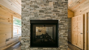 A stone fireplace with a glass door, wooden walls, and a wooden door to the right. - Silver City Mountain Resort (Three Rivers)