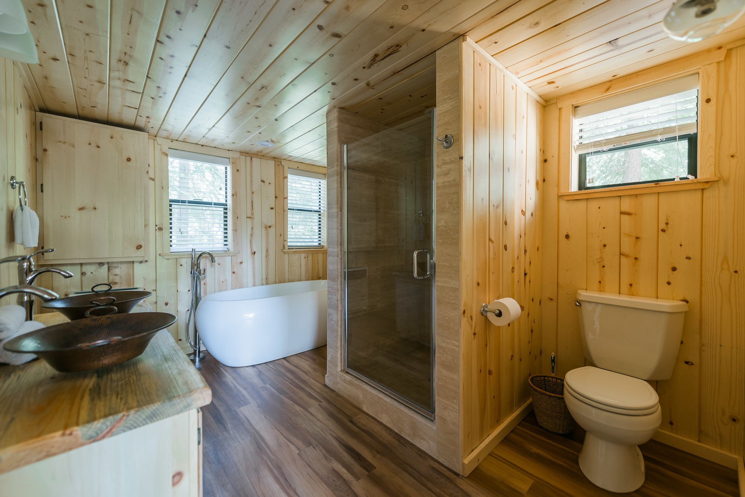 Un baño de cabaña de madera con bañera, inodoro y ducha.