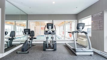 Gimnasio con máquinas de cardio, piscina y un cartel de normas de seguridad.