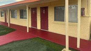Un motel con toldo rojo, puertas numeradas y un pasillo rojo.