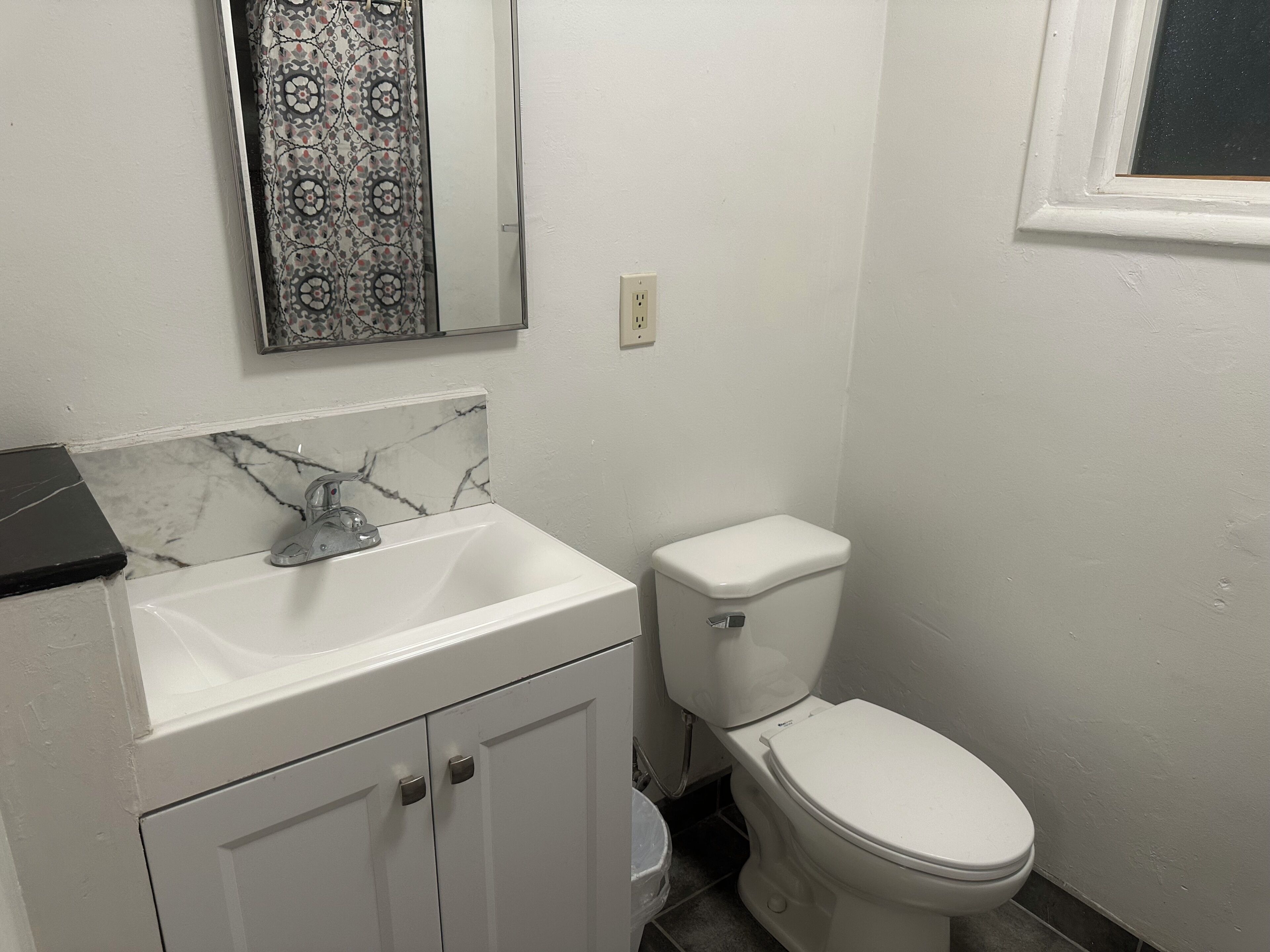 A bathroom with a white sink, a toilet, and a mirror.