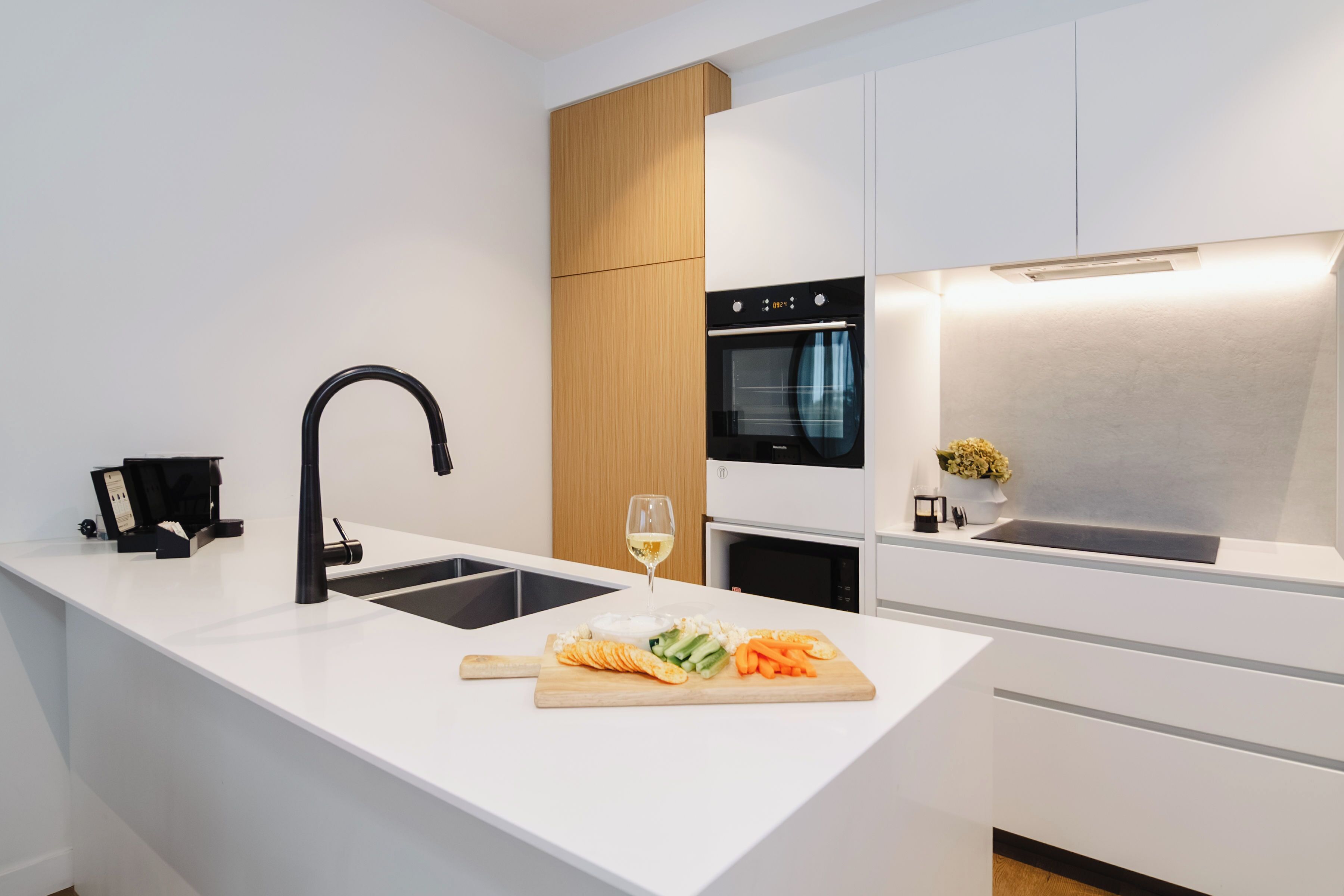 Una cocina moderna con una isla central, horno empotrado y un grifo elegante.