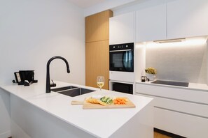A modern kitchen with a central island, a built-in oven, and a sleek faucet. - Punthill Ivanhoe (Ivanhoe)