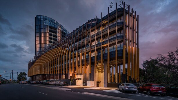 Un edificio moderno con fachada de vidrio curvo y una serie de listones verticales de madera.