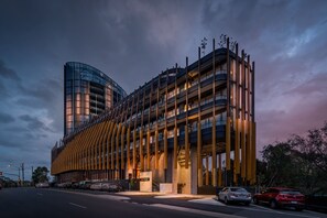Un edificio moderno con fachada de vidrio curvo y una serie de listones verticales de madera.