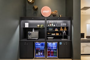 A minibar with a coffee machine, wine bottles, snacks, and a refrigerator stocked with beverages.