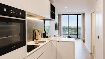 A modern kitchen with a built-in oven, a coffee machine, and a large window offering a view of the outdoors.