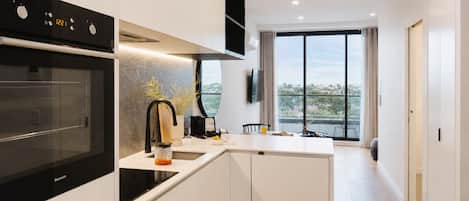 Una cocina moderna con horno integrado, cafetera y un amplio ventanal con vistas al exterior.
