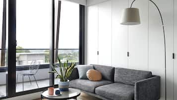 Ein modernes Wohnzimmer mit grauem Sofa, rundem Couchtisch, Zimmerpflanze und Stehlampe.