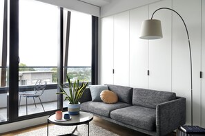 A modern living room with a grey sofa, a round coffee table, a potted plant, and a floor lamp. - Punthill Ivanhoe (Ivanhoe)