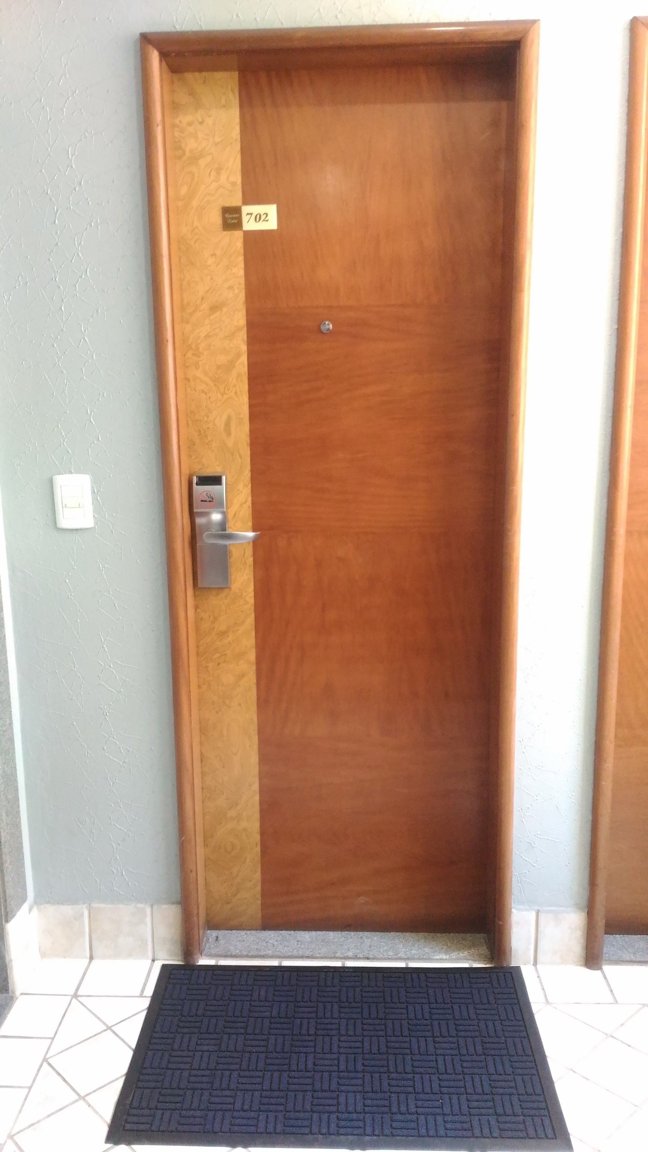 A wooden door with a metal handle and a keyhole, marked with the number 702.