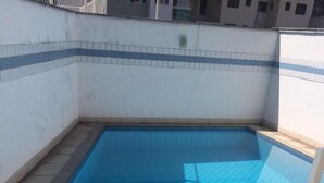 Una piscina rectangular con suelo de azulejos y una escalera metálica.