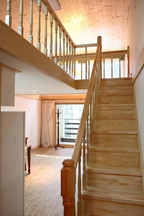 A wooden staircase with a railing leading to an upper floor.