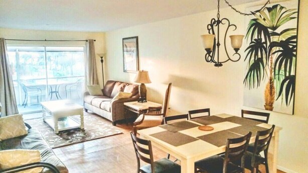 Ein geräumiger Wohnbereich mit Esstisch, Stühlen, einer Couch und einer Lampe.