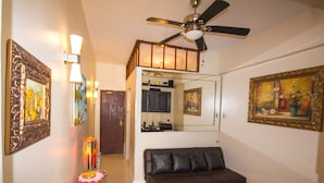 A living room with a brown leather sofa, a ceiling fan, and framed artwork on the walls. - Copacabana Near the Beach (Rio de Janeiro)