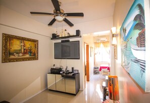 A living room with a ceiling fan, a flat-screen TV mounted on the wall, a cabinet with electronic devices, and a painting on the wall. - Copacabana Near the Beach (Rio de Janeiro)