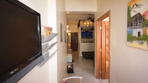 A hallway with a flat-screen TV, a bookshelf, a painting, and a dining area with a table and chairs. - Copacabana Near the Beach (Rio de Janeiro)