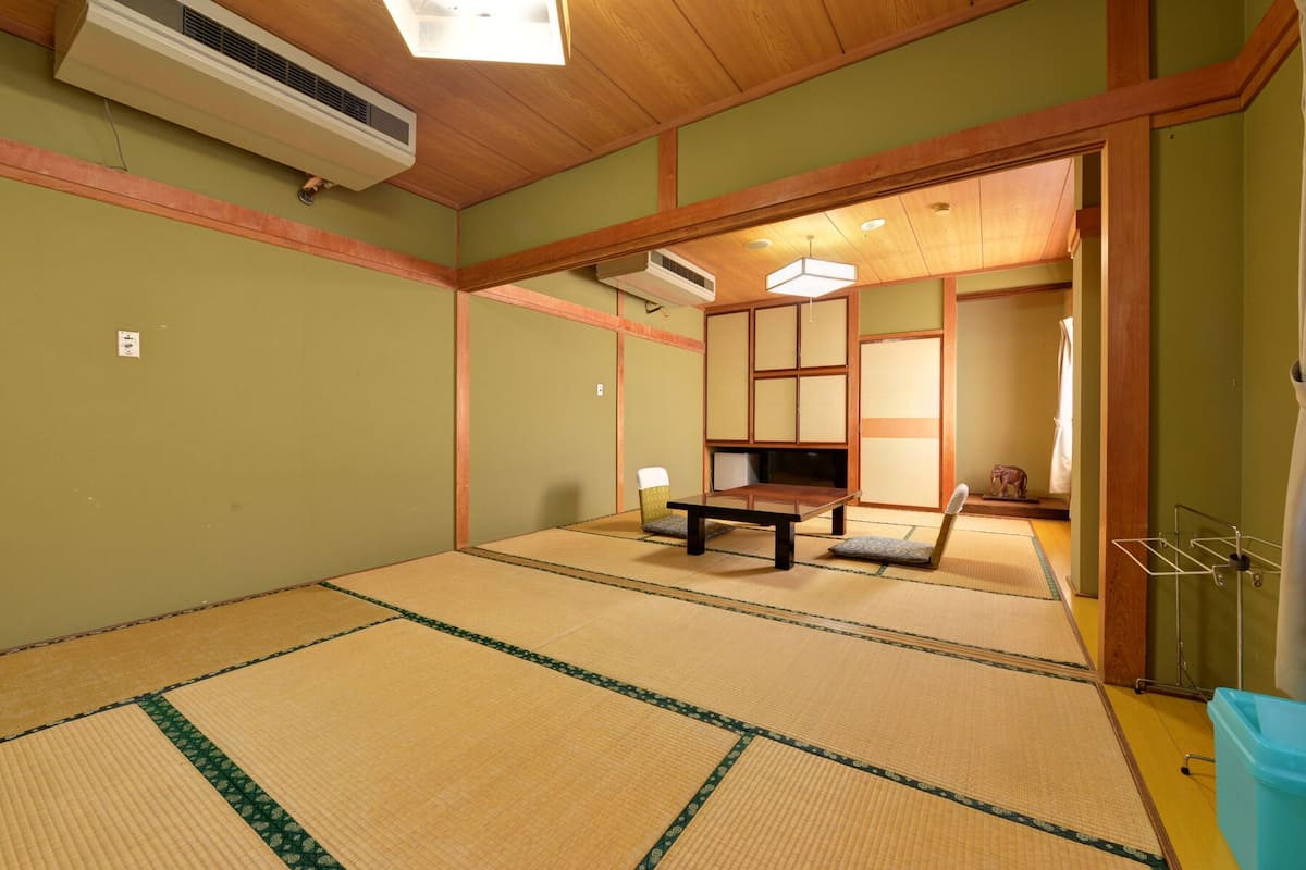 A tatami mat room with a wooden table, a futon bed, and a traditional Japanese sliding door.