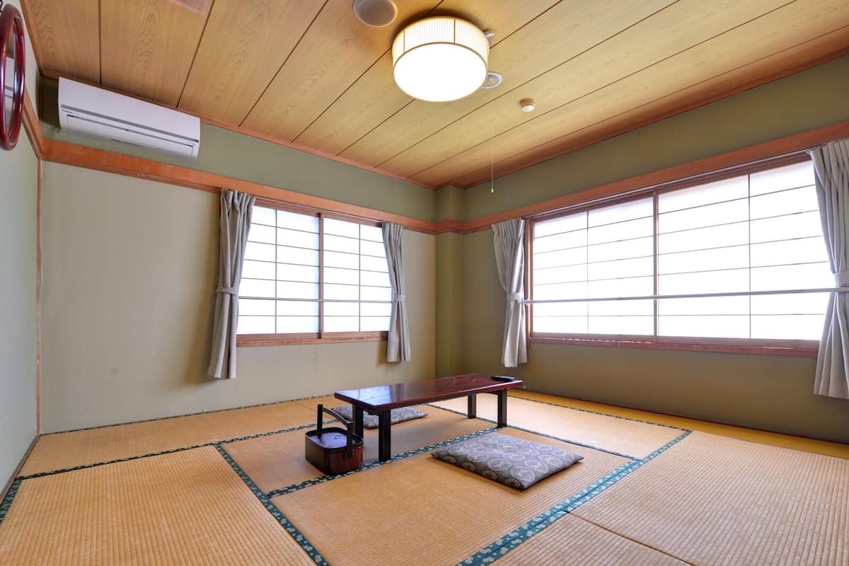 A tatami mat room with a wooden ceiling, a small table, and a cushion.