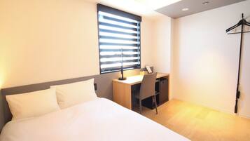 A modern hotel room with a bed, a desk, and a chair.