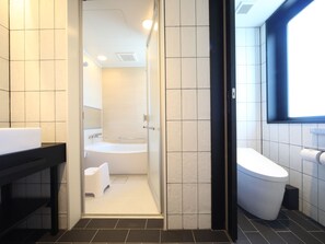Une salle de bain moderne équipée d’une baignoire, de toilettes et d’un espace douche.