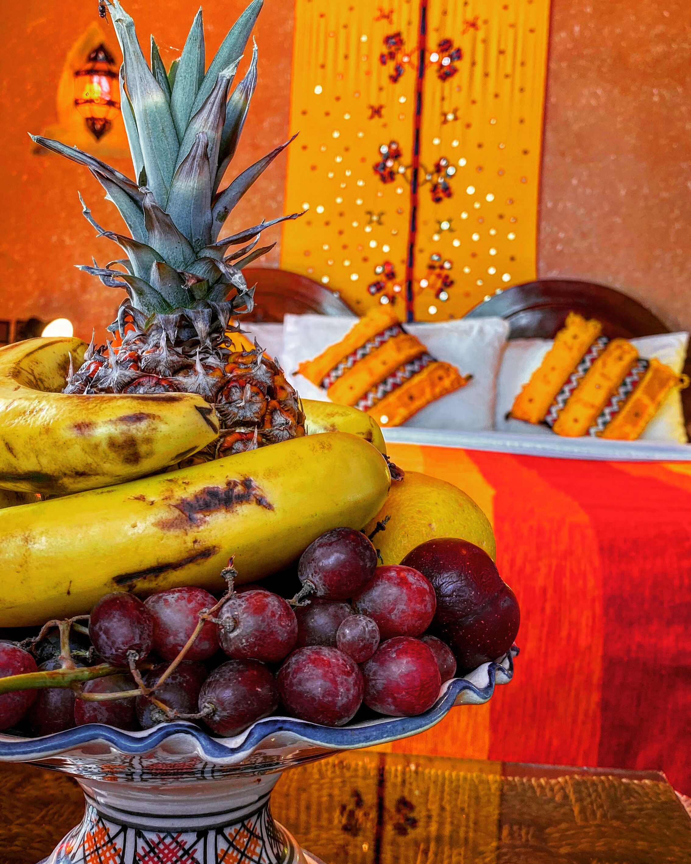 Un piatto decorativo con un vassoio di frutta, banane, uva e un'ananas.