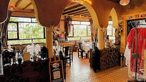 A restaurant with a rustic interior, featuring stone walls, wooden beams, and large windows. There is a sign indicating Wi-Fi availability. - Riad Chay & Boutique (Tarmigt)