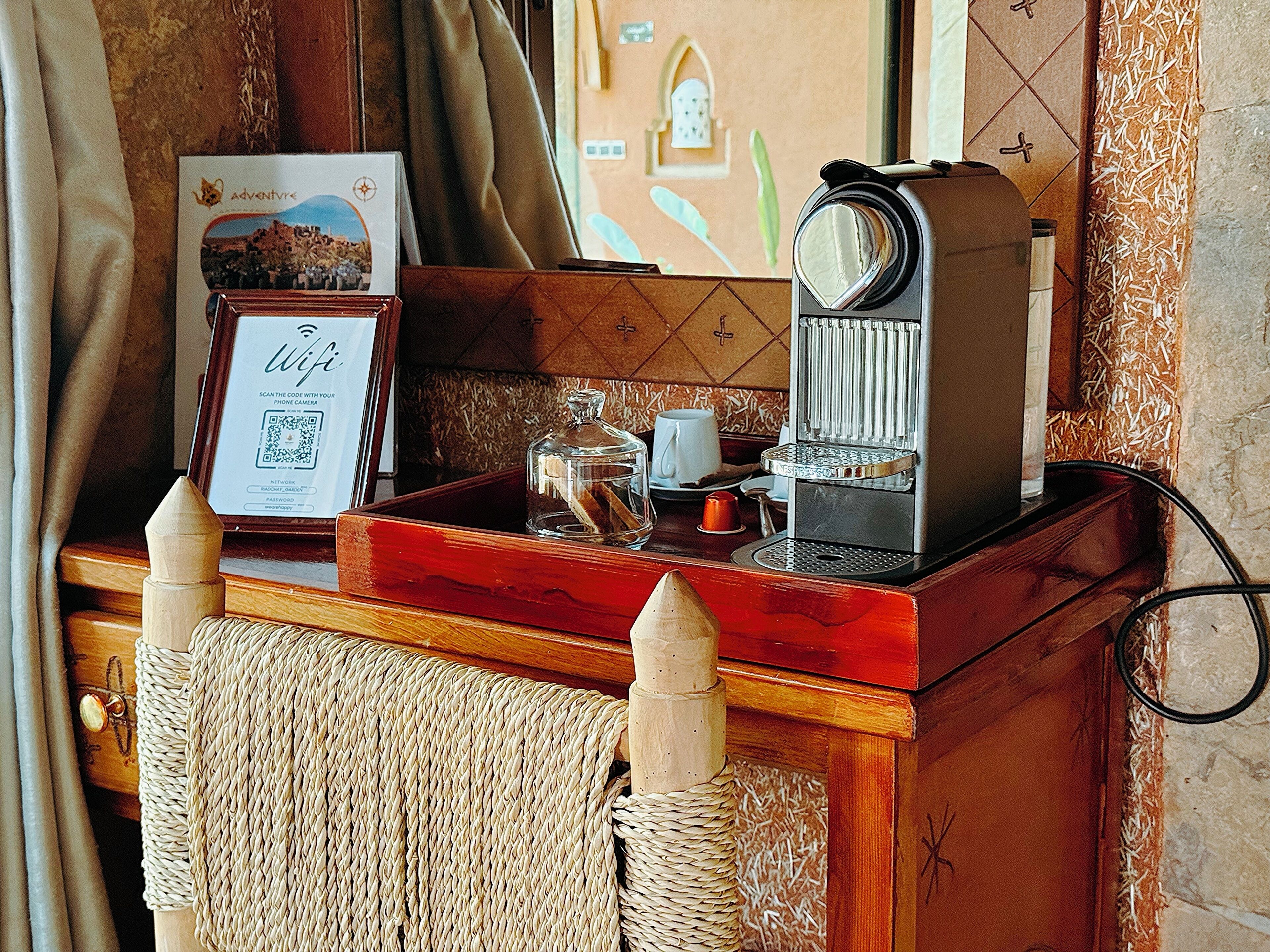 Una barra de madera con una máquina de café, un certificado enmarcado y un recipiente de vidrio decorativo.