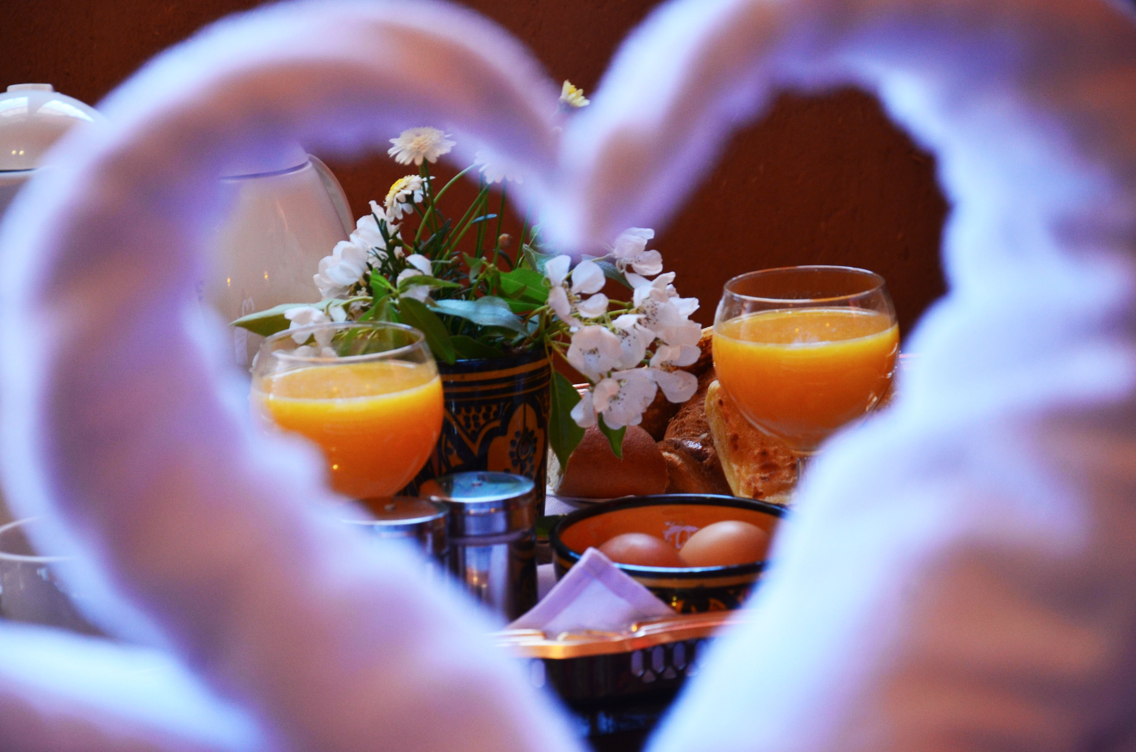 A breakfast table with orange juice, eggs, and bread.