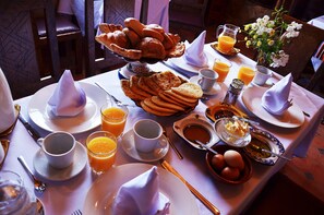 A breakfast setting with bread, eggs, and orange juice on a table.