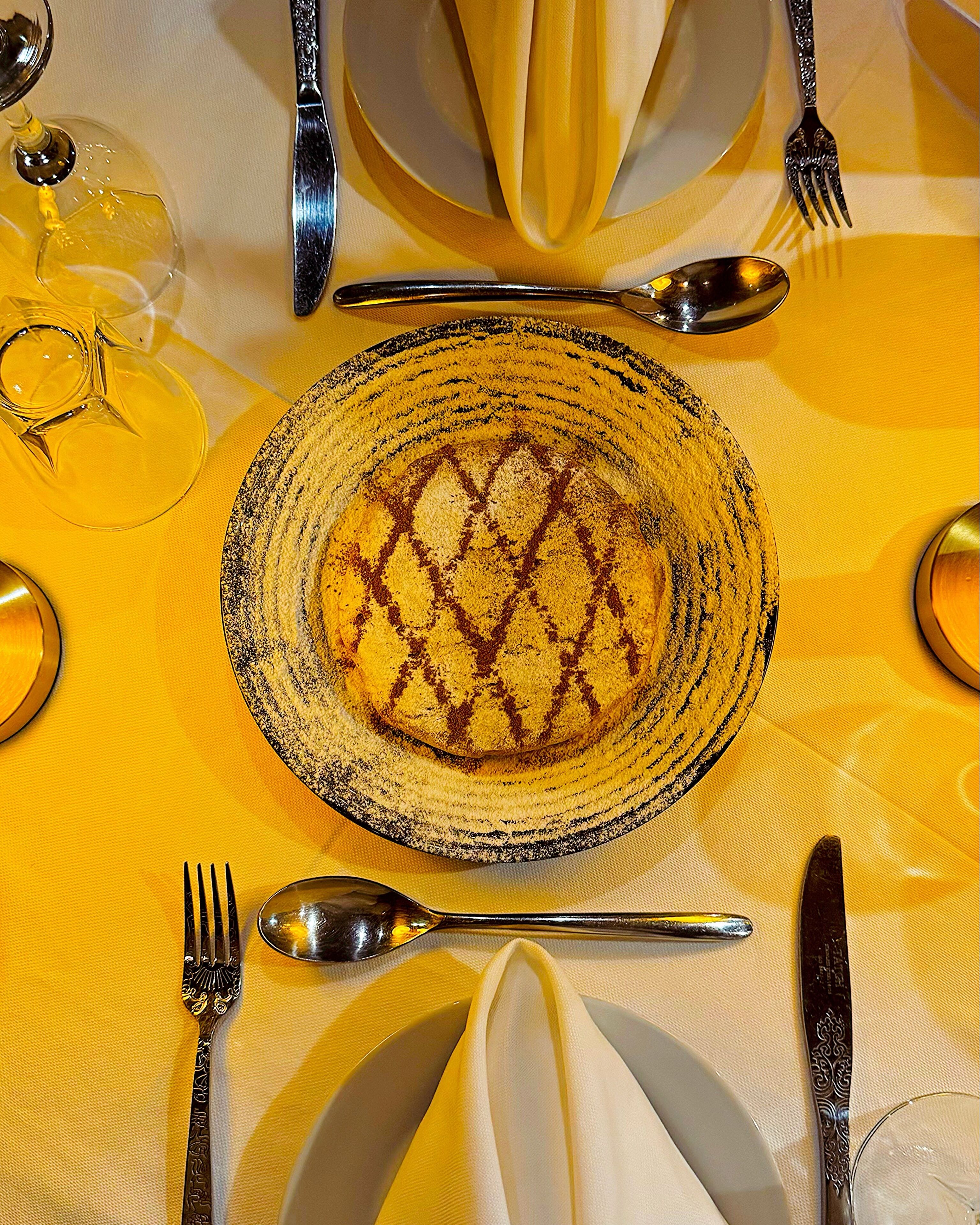A table set with a patterned plate, silverware, and a glass.
