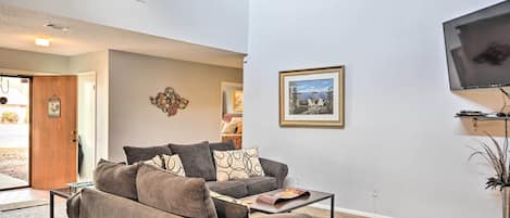 A living room with a sofa, coffee table, and a mounted TV.