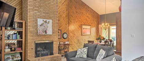 A living room with a brick fireplace, a sofa, a coffee table, and a bookshelf.